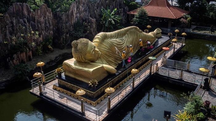 TOPSHOT - Workers clean a Buddha statue at Maha Vihara Mojopahit temple in Mojokerto on May 30, 2023, ahead of the Vesak festival which commemorates the birth, enlightenment and death of Buddha. (Photo by JUNI KRISWANTO / AFP) (Photo by JUNI KRISWANTO/AFP via Getty Images)
