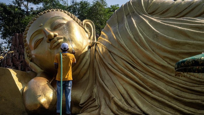 TOPSHOT - Workers clean a Buddha statue at Maha Vihara Mojopahit temple in Mojokerto on May 30, 2023, ahead of the Vesak festival which commemorates the birth, enlightenment and death of Buddha. (Photo by JUNI KRISWANTO / AFP) (Photo by JUNI KRISWANTO/AFP via Getty Images)
