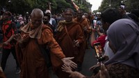 Sejumlah biksu peserta ritual Thudong menyapa warga yang menyambut di pinggir jalan raya kota Magelang, Jawa Tengah, Selasa (30/5/2023). (Aditya Irawan/NurPhoto via Getty Images)