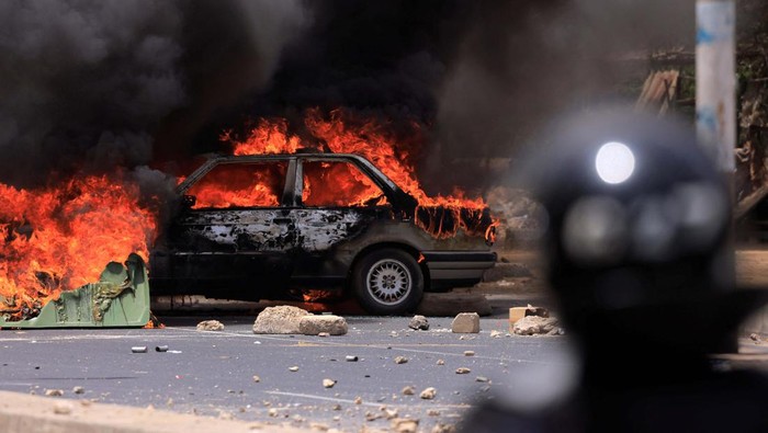 Riot police officers walk near a car set on fire during clashes between supporters of Senegalese opposition leader Ousmane Sonko and security forces after Sonko was sentenced to prison in Dakar Senegal June 1, 2023 REUTERS/Zohra Bensemra
