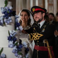 Rajwa Al Saif tampil memesona di hari pernikahannya saat menyapa para warga di luar Istana Zahran Yordania. Sosok Rajwa sudah kerap muncul di Yordania setelah tunangan dengan Pangeran Hussein pada Agustus 2022. Foto: Dok. Getty Images, Instagram Queen Rania