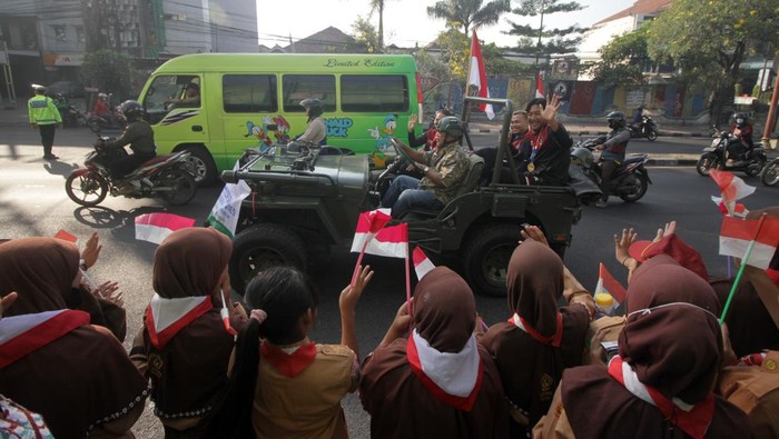 Atlet SEA Games 2023 Kamboja asal Sidoarjo berdiri di atas kendaraan saat melintas di jalan A. Yani Sidoarjo, Jawa Timur, Sabtu (3/6/2023). Sebanyak delapan atlet asal Sidoarjo memperoleh penghargaan dan apresiasi dari Pemkab setempat menyusul keberhasilan mereka meraih enam medali emas, sebuah medali perak dan tiga medali perunggu di SEA Games 2023 Kamboja. ANTARA FOTO/Umarul Faruq/nym.