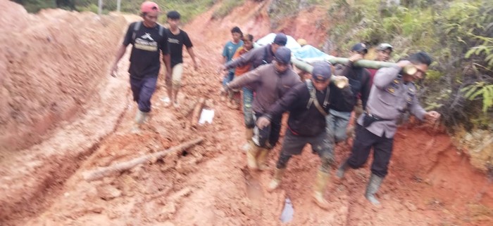 Warga bersama polisi menandu jasad tukang ojek melewati jalan rusak di Seko, Luwu Utara, Sulsel.