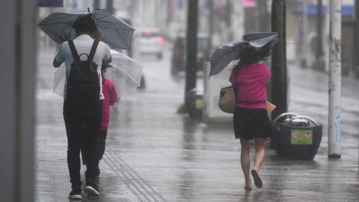 People walk down the famed Kokusai-dori street, a tourist spot, in Naha in the main Okinawa island, southern Japan, Thursday, June 1, 2023, as a tropical storm was approaching. (AP Photo/Hiro Komae)