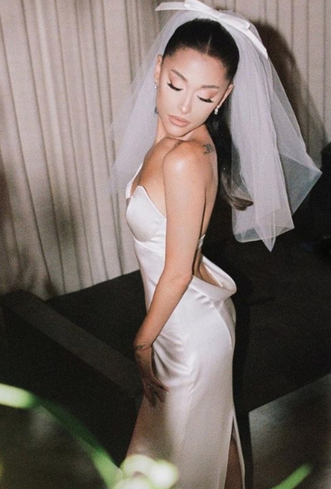 Ariana Grande menikah dengan kekasihnya Dalton Gomez pada Mei 2021. Gaun pengantinnya tampak simple dengan potongan strapless dan detail cutout pada bagian punggungnya. Foto: Instagram @arianagrande