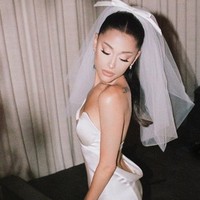 Ariana Grande menikah dengan kekasihnya Dalton Gomez pada Mei 2021. Gaun pengantinnya tampak simple dengan potongan strapless dan detail cutout pada bagian punggungnya. Foto: Instagram @arianagrande
