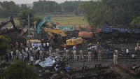Polisi berjaga di lokasi kereta tergelincir, di distrik Balasore, di negara bagian Odisha timur, India timur, Minggu (4/6/2023). Otoritas India mengakhiri pekerjaan penyelamatan dan mulai membersihkan puing-puing dua kereta penumpang yang tergelincir tersebut.