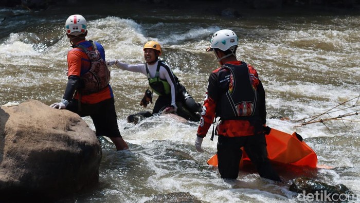 Petugas mengevakuasi jasad pemancing yang tewas digulung arus Sungai Cimanuk.