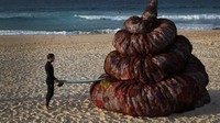 Seorang peselancar melihat karya seni buatan Better Packaging Co. di Bondi Beach, Sydney, Australia, Senin (5/6/2023). Karya itu dibuat dalam rangka memperingati hari lingkungan hidup sedunia.