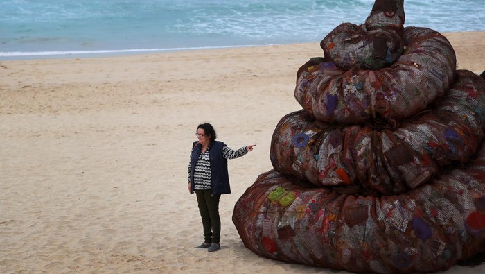 SYDNEY, AUSTRALIA - JUNE 05: A surfer interacts with a sculpture titled 'Plastic pile of sh!t, 2023' presented by Better Packaging Co. at Bondi Beach on June 05, 2023 in Sydney, Australia. The four-metre-high sculpture is made out of recycled plastic and resembles human feces. The sculpture is designed to draw attention to the amount of plastic that's dumped in the world's oceans every 30 seconds. (Photo by Lisa Maree Williams/Getty Images)