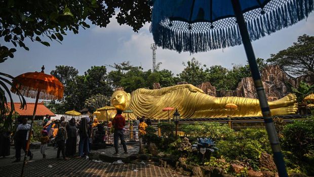 Tourists visit a giant Buddha statue at Maha Vihara Mojopahit temple in Mojokerto on June 4, 2023, as Buddha devotees celebrate Vesak day. (Photo by Juni Kriswanto / AFP) (Photo by JUNI KRISWANTO/AFP via Getty Images)
