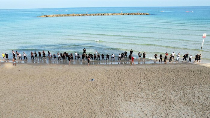 Olahraga di Pantai, Cara Warga Palestina Melepas Penat dari Kota Members of a fitness group of Palestinians from East Jerusalem work out on a beach in Tel Aviv, Israel May 26, 2023. REUTERS/Ammar Awad