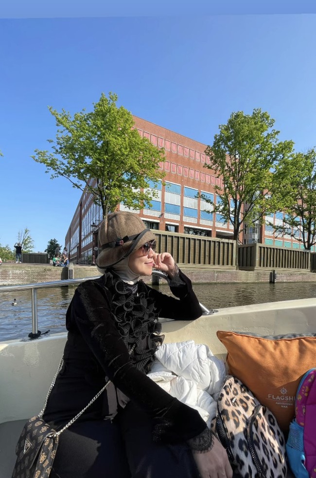 Ini gaya Venna Melinda saat menikmati liburan di Belanda. Ia mengenakan long dress hitam dengan aksen ruffle pada bagian dada. Penampilan Venna Melinda pun disempurnakan dengan topi cokelat yang senada dengan tasnya. Foto: Dok. Instagram Venna Melinda