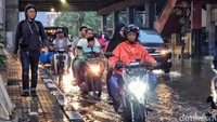 Beberapa pemotor tampak menerobos genangan dengan hati-hati.