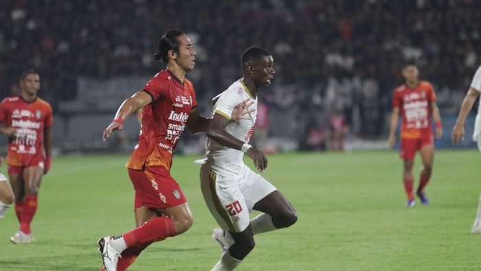 Pemain PSM Makassar Adilson Silva mendapat hadangan Bali United Ryuji Utama.