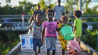 Sejumlah anak membawa ember untuk mengambil air bersih dari reservoir penampung air hujan fasilitas dari pemerintah di Distrik Agats, Kabupaten Asmat, Papua Selatan.  