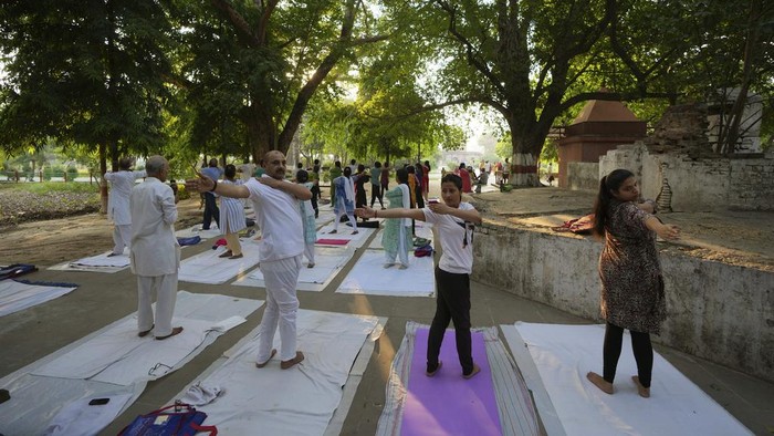 People perform yoga in a group at the Khusro Bagh garden and burial complex in Prayagraj, India, early Tuesday, June 6, 2023. The three sandstone mausoleums within this walled garden are an example of Mughal architecture. The design of its main entrance, the surrounding gardens and the three-tier tomb of Shah Begum, who died in 1604, has been attributed to Aqa Reza, Jahangir's principal court artist. Shah Begum, originally Manbhawati Bai, was the daughter of Raja Bhagwant Das of Amber. (AP Photo/Rajesh Kumar Singh)