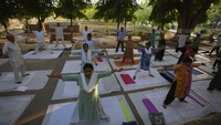 Orang-orang melakukan yoga di kompleks pemakaman di Prayagraj, India, Selasa (6/5/2023).