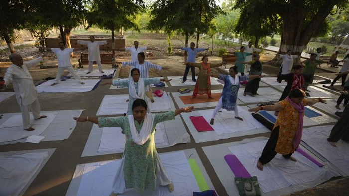 People perform yoga in a group at the Khusro Bagh garden and burial complex in Prayagraj, India, early Tuesday, June 6, 2023. The three sandstone mausoleums within this walled garden are an example of Mughal architecture. The design of its main entrance, the surrounding gardens and the three-tier tomb of Shah Begum, who died in 1604, has been attributed to Aqa Reza, Jahangir's principal court artist. Shah Begum, originally Manbhawati Bai, was the daughter of Raja Bhagwant Das of Amber. (AP Photo/Rajesh Kumar Singh)