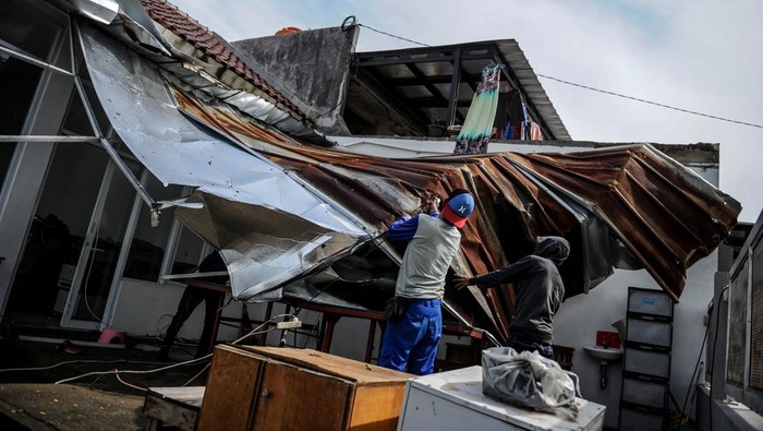 141 Rumah Rusak Gegara Puting Beliung di Kabupaten Bandung Warga bersama petugas BPBD menebang pohon yang rawan tumbang setelah terjadi bencana angin puting beliung di Bojong Malaka, Baleendah, Kabupaten Bandung, Jawa Barat, Rabu (7/62023). Pemerintah Kabupaten Bandung mencatat sebanyak 141 rumah di tiga kelurahan di Kecamatan Baleendah mengalami kerusakan ringan hingga berat akibat bencana angin puting beliung yang terjadi pada Senin (5/6/2023) petang. ANTARA FOTO/Raisan Al Farisi