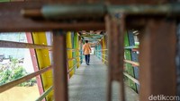 Pintu pagar JPO dikunci permanen membuat warga terpaksa merayap di sisi jembatan.   