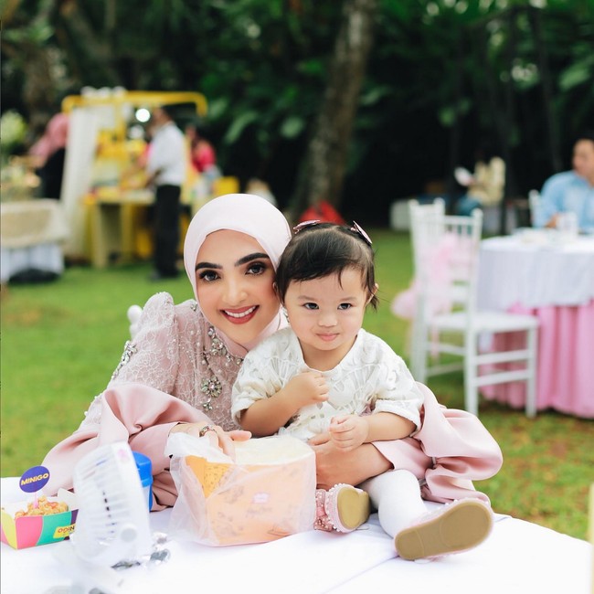 Ashanty, ibu sambung Aurel, tampil dengan busana hijab, bergaya girlie mengenakan setelan tunik dan celana panjang warna dusty pink. Busananya dipercantik detail lace, mutiara dan perhiasan kristal. Foto: Instagram