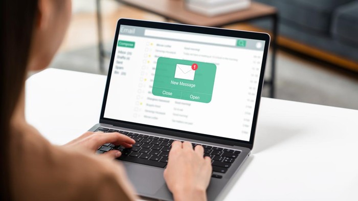 Woman using computer on table with new email message on laptop, communication connection message to global letters in the workplace