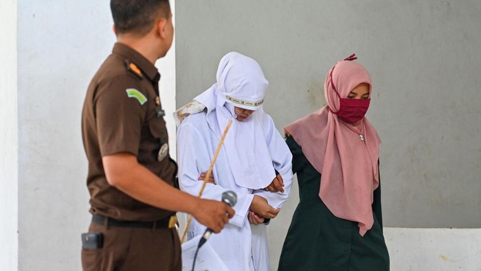 Melihat Eksekusi Hukum Cambuk di Aceh A woman (C) reacts while being caned by members of the Sharia police as punishment for being caught in close proximity with a man in Banda Aceh on June 7, 2023. (Photo by CHAIDEER MAHYUDDIN / AFP) (Photo by CHAIDEER MAHYUDDIN/AFP via Getty Images)