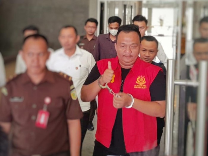 Sisco mengacungkan jempolnya ke wartawan usai diserahkan polisi ke Kejati Sumsel. Foto: Prima Syahbana/detikSumbagsel