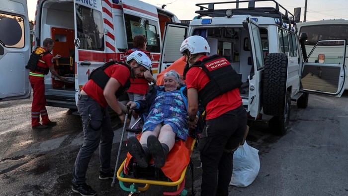 Puluhan Ribua Warga Dievakuasi Akibat Jebolnya Bendungan Kakhovka Red Cross volunteers help an elderly woman evacuated from a flooded area after the Nova Kakhovka dam breached, amid Russia's attack on Ukraine, in Kherson, Ukraine June 6, 2023. REUTERS/Ivan Antypenko
