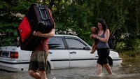 Penduduk setempat membawa barang-barang pribadi mereka di jalan yang banjir, setelah bendungan Nova Kakhovka jebol, di tengah serangan Rusia di Ukraina, di Kherson, Ukraina, Selasa (6/6/2023).