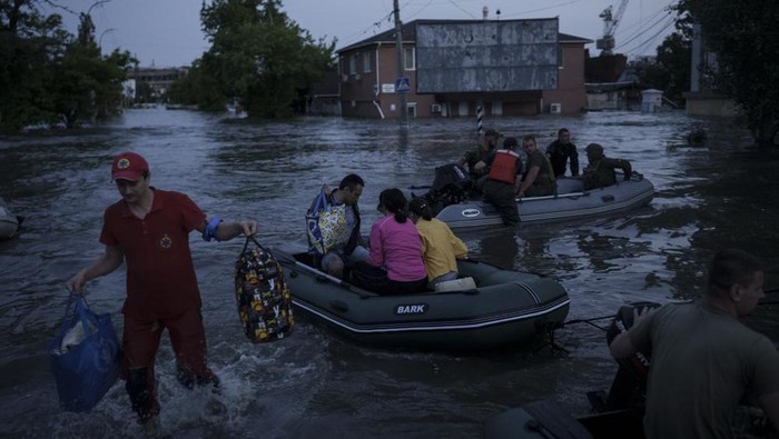 An emergency worker carries belongings of residents being evacuated from a flooded neighborhood in Kherson, Ukraine, Tuesday, June 6, 2023. A major dam in southern Ukraine has collapsed, flooding villages, endangering crops in the countrys breadbasket and threatening drinking water supplies. (AP Photo/Felipe Dana)