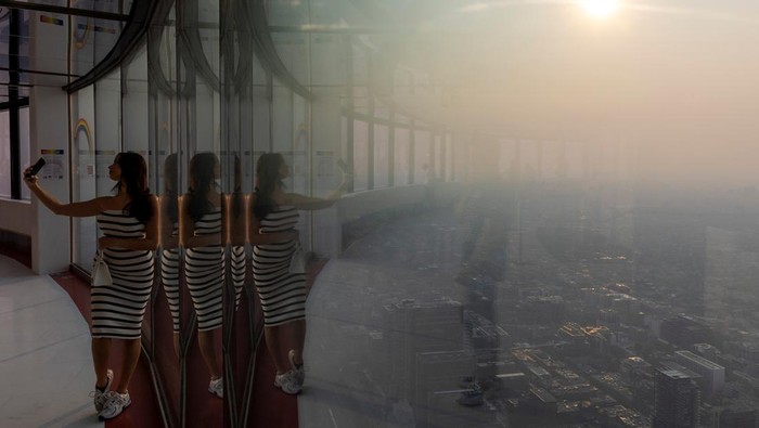 Warga Kanada Asyik Selfie Saat Kota Dikepung Asap Kebakaran Hutan A person looks down towards the city as a smokey Toronto is seen from the CN Tower as wildfires in Ontario and Quebec continue to burn, in Toronto, Ontario, Canada June 6, 2023. REUTERS/Carlos Osorio TPX IMAGES OF THE DAY