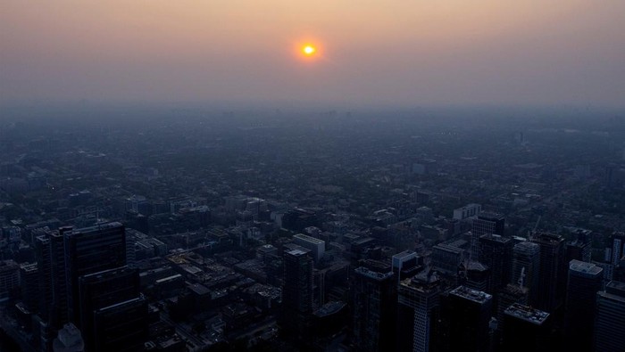 A person looks down towards the city as a smokey Toronto is seen from the CN Tower as wildfires in Ontario and Quebec continue to burn, in Toronto, Ontario, Canada June 6, 2023. REUTERS/Carlos Osorio     TPX IMAGES OF THE DAY