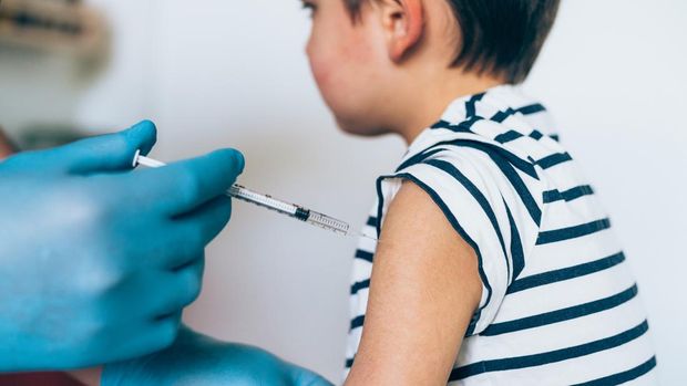 Hands of doctor in medical gloves injecting vaccine to a child patient. Doctor giving muscular injection to little child in arm. Vaccination healthcare concept.