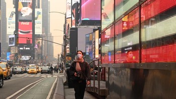 Seorang wanita memakai masker berjalan di Times Square, New York. Pejabat Kanada mengatakan fenomena ini akan menjadi musim kebakaran terburuk di negara itu, terkait tanah yang lebih kering dari biasanya dan api berakselerasi dengan cepat. Foto: Getty Images