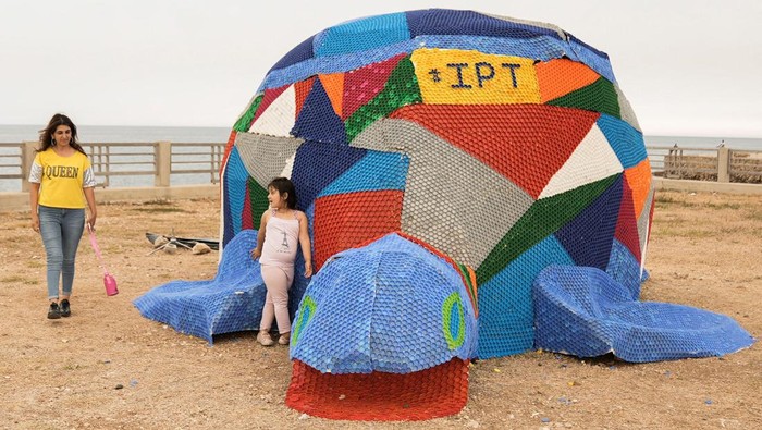 Kampanye Lingkungan, Aktivis Bikin Penyu Warna-warni dari Botol Plastik Graphic designer Sahar Ghouche walks with her daughter Christy Maria next to a turtle made from plastic caps and bottles in Amchit, Lebanon June 1, 2023. REUTERS/Issam Abdallah