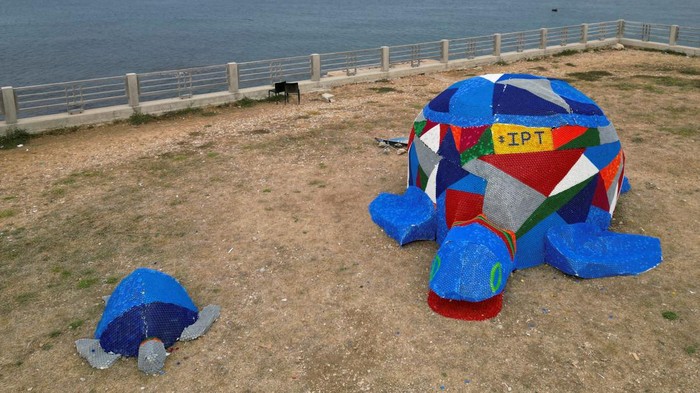 Kampanye Lingkungan, Aktivis Bikin Penyu Warna-warni dari Botol Plastik Graphic designer Sahar Ghouche walks with her daughter Christy Maria next to a turtle made from plastic caps and bottles in Amchit, Lebanon June 1, 2023. REUTERS/Issam Abdallah