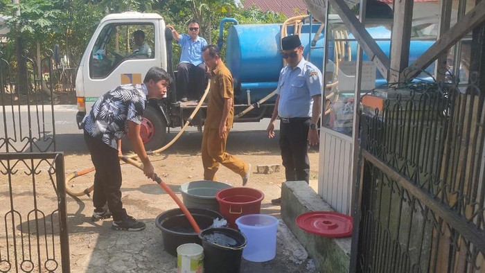 Petugas PDAM mengisi air ke rumah warga