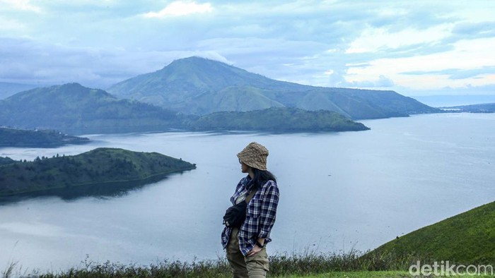 Pengunjung berfoto di Bukit Holbung, Samosir, Sumatera Utara, Rabu (15/2/2023). Keindahan bukit ini dapat dinikmati wisatawan hanya dengan menaiki anak tangga.