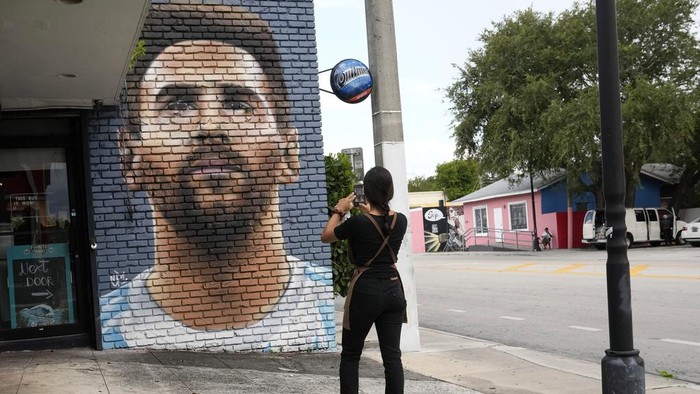 Jessica Ospina takes a photograph of a mural of Lionel Messi outside of the Fiorito restaurant, Wednesday, June 7, 2023, in Miami. The Argentine soccer star announced Wednesday he is joining the Inter Miami Major League Soccer team. (AP Photo/Lynne Sladky)
