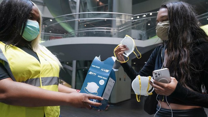 MTA employee Shanita Hancle, left, hands out masks to commuters at the entrance to a subway station in New York, Thursday, June 8, 2023. Air pollution from Canadian wildfires are cloaking the northeastern U.S. for a second day. (AP Photo/Seth Wenig)