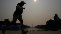 Seorang pelari berlari di bawah kabut yang menyelimuti Kolam Refleksi dengan Monumen Washington terlihat dari kejauhan. AP/Julio Cortez  