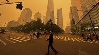 Pejalan kaki melewati One World Trade Center di tengah kabut asap akibat kebakaran hutan. AP/Julie Jacobson  