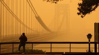 Seorang pria berbicara di teleponnya saat dia melihat menembus kabut di Jembatan George Washington dari Fort Lee, NJ. AP/Seth Wenig  