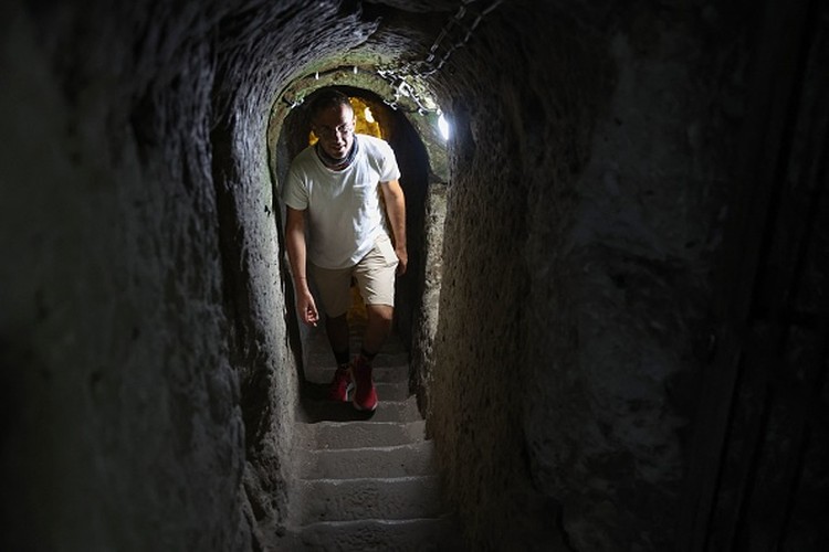 1242703631 A tourist walks through a passage in the Derinkuyu underground city, in Turkeys central Nevsehir province, on August 24, 2022. - The ancient city of Elengubu, known today as Derinkuyu, reaches the depth of 85m below the Earths surface, and could accommodate up to 20,000 people. (Photo by OMAR HAJ KADOUR / AFP) (Photo by OMAR HAJ KADOUR/AFP via Getty Images)