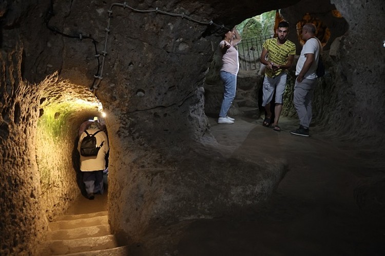 1242703631 A tourist walks through a passage in the Derinkuyu underground city, in Turkeys central Nevsehir province, on August 24, 2022. - The ancient city of Elengubu, known today as Derinkuyu, reaches the depth of 85m below the Earths surface, and could accommodate up to 20,000 people. (Photo by OMAR HAJ KADOUR / AFP) (Photo by OMAR HAJ KADOUR/AFP via Getty Images)