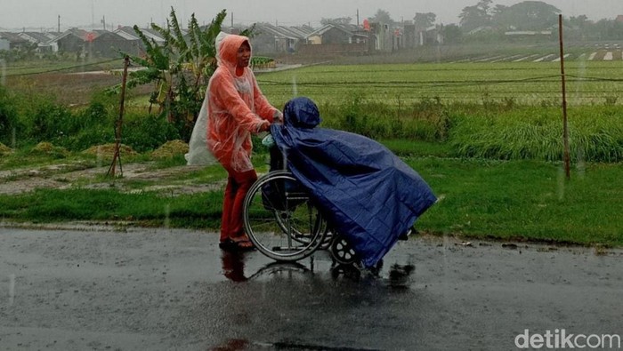 Aan, warga Brebes terpaksa mendorong kursi roda bawa suami ke RS untuk berobat.