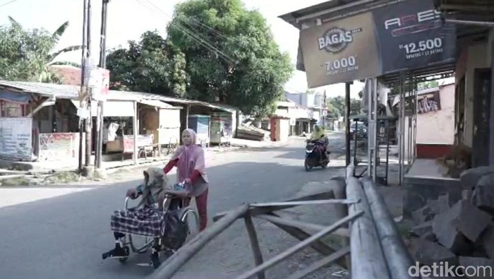 Aan, warga Brebes terpaksa mendorong kursi roda bawa suami ke RS untuk berobat.