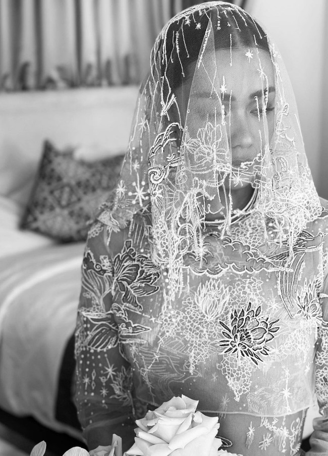Gaun pengantin dilengkapi atasan crop top lengan panjang yang memberi dimensi pada keseluruhan busana. Ditambah veil bermotif sama menambah kesan dramatis nan romantis. Foto: Instagram